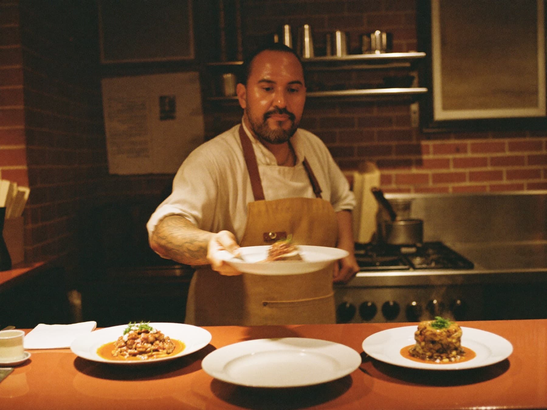 A cook sliding a finished plate across the pass